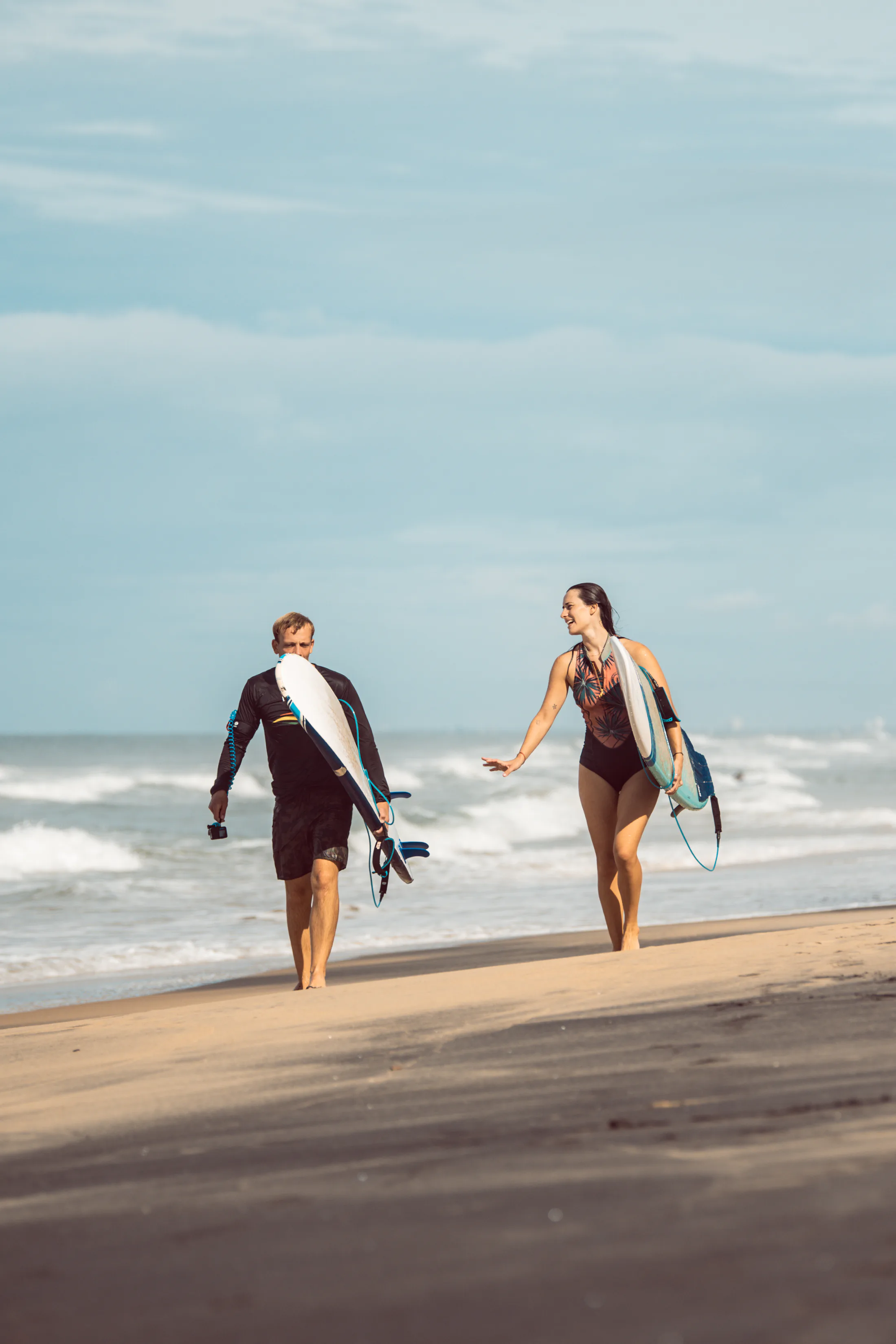 Friends walking to the ocean with surfboards at Paddlecult