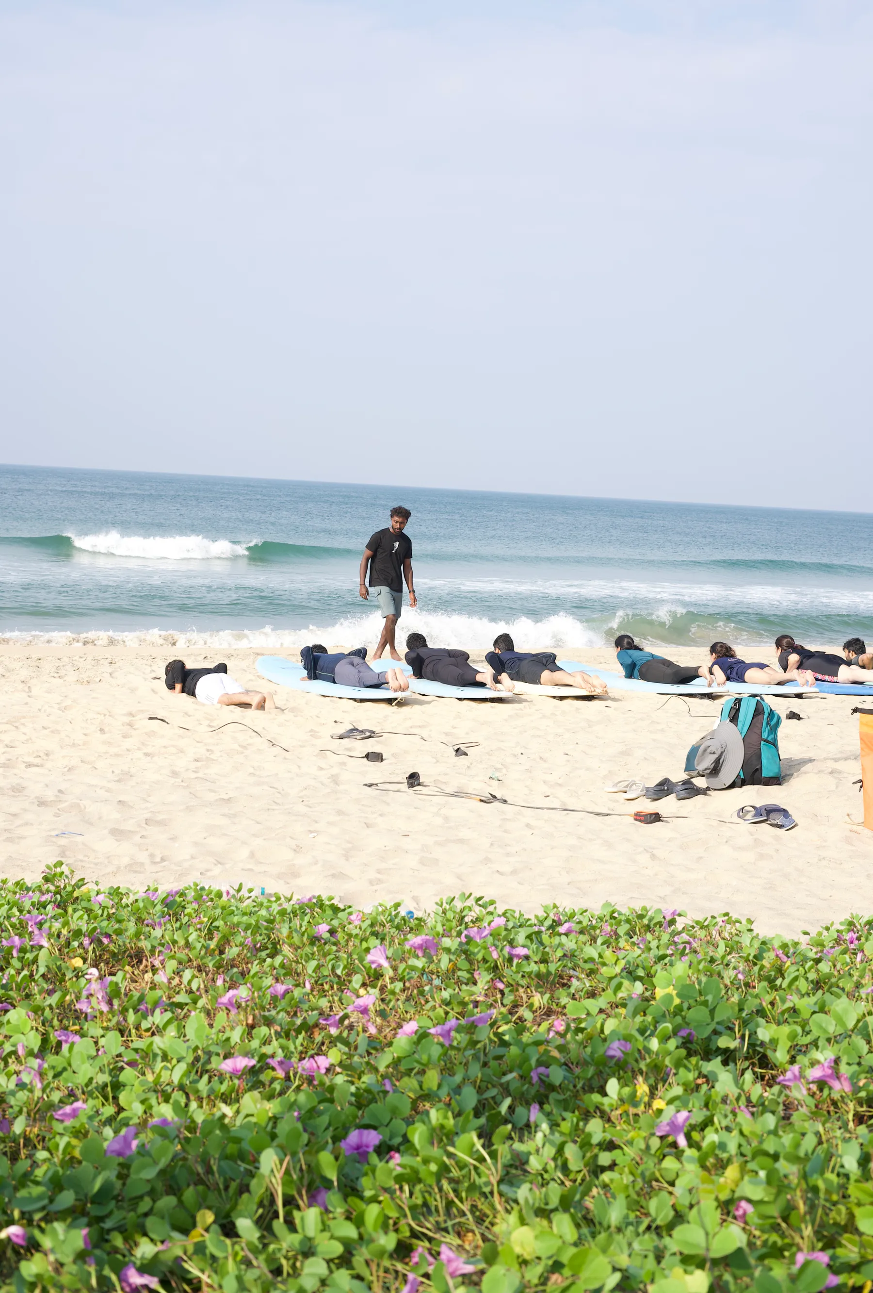 A surf instructor guiding learners on the sand
