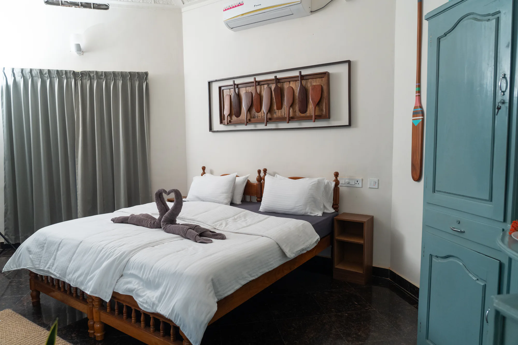 A Paddlecult bedroom with white bedding, wooden paddles and a blue wardrobe