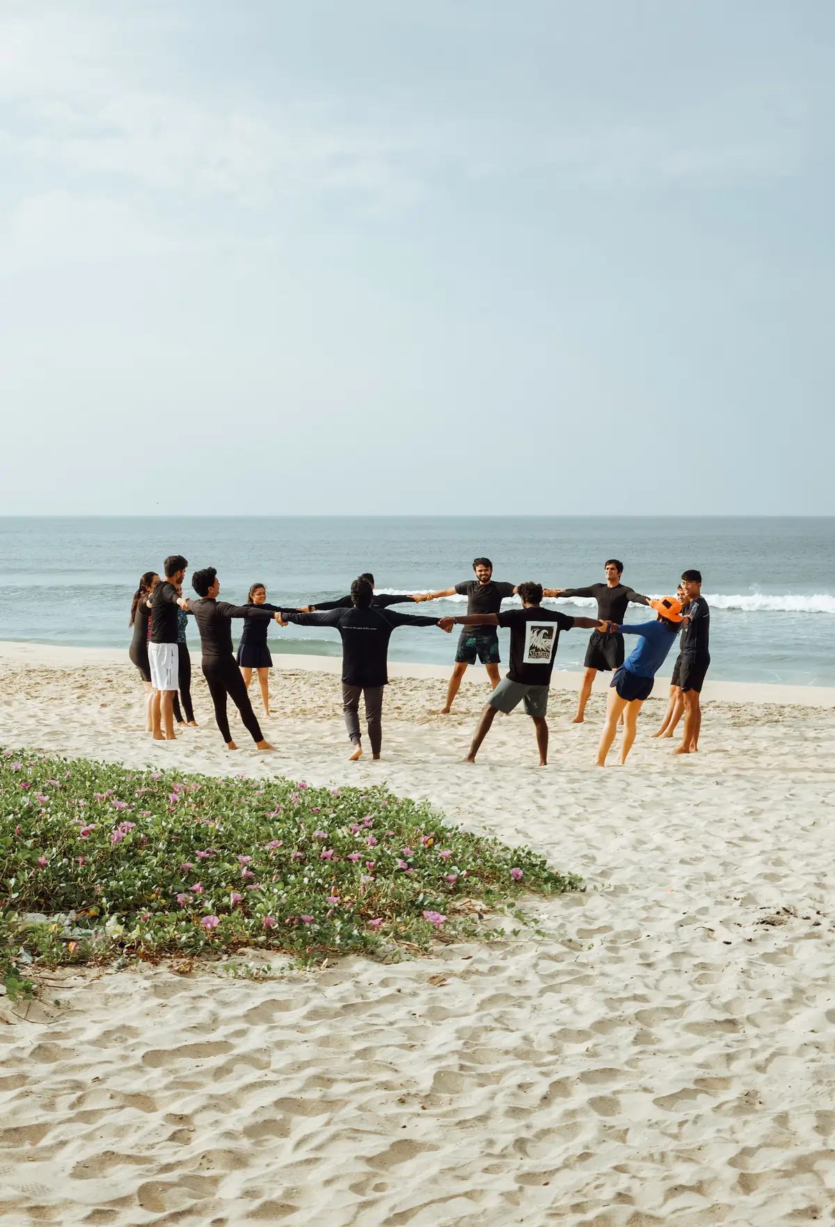 Surfers warming up in a circle on the beach